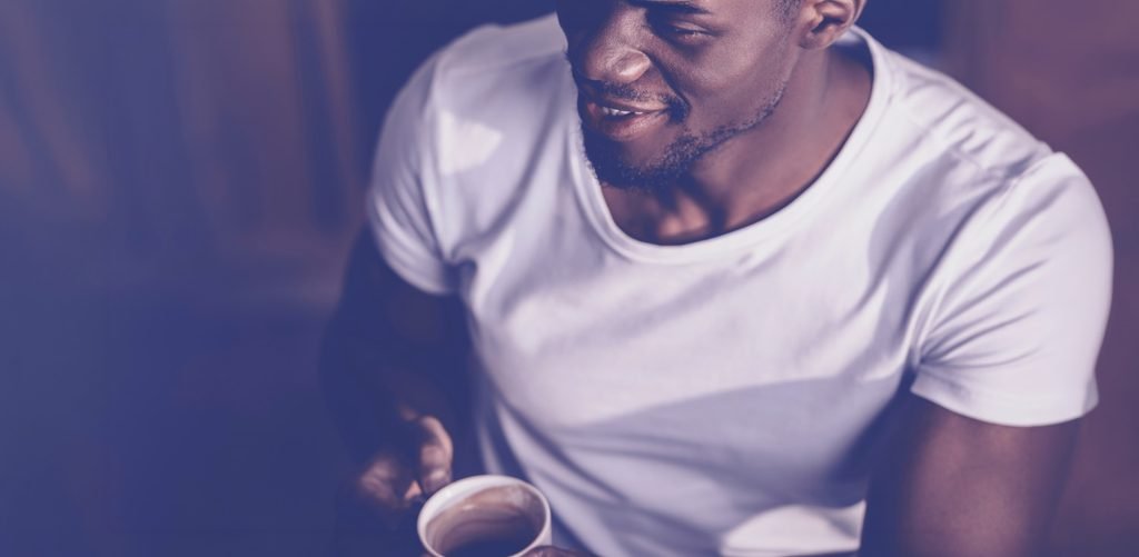 I Know This About Myself A man in a white T-shirt holds a cup of coffee in soft sunlight.